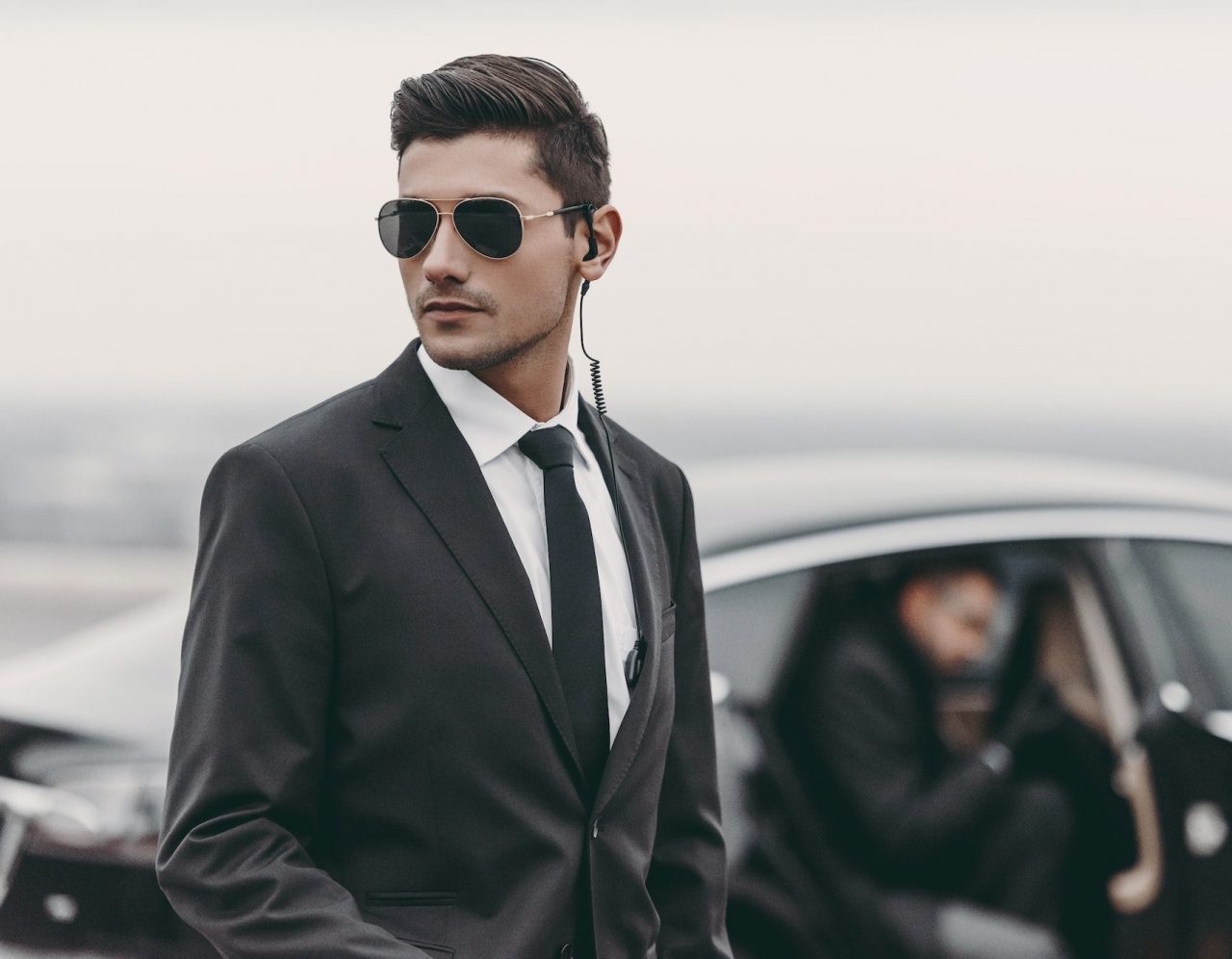 bodyguard reviewing territory while businessman going out from car